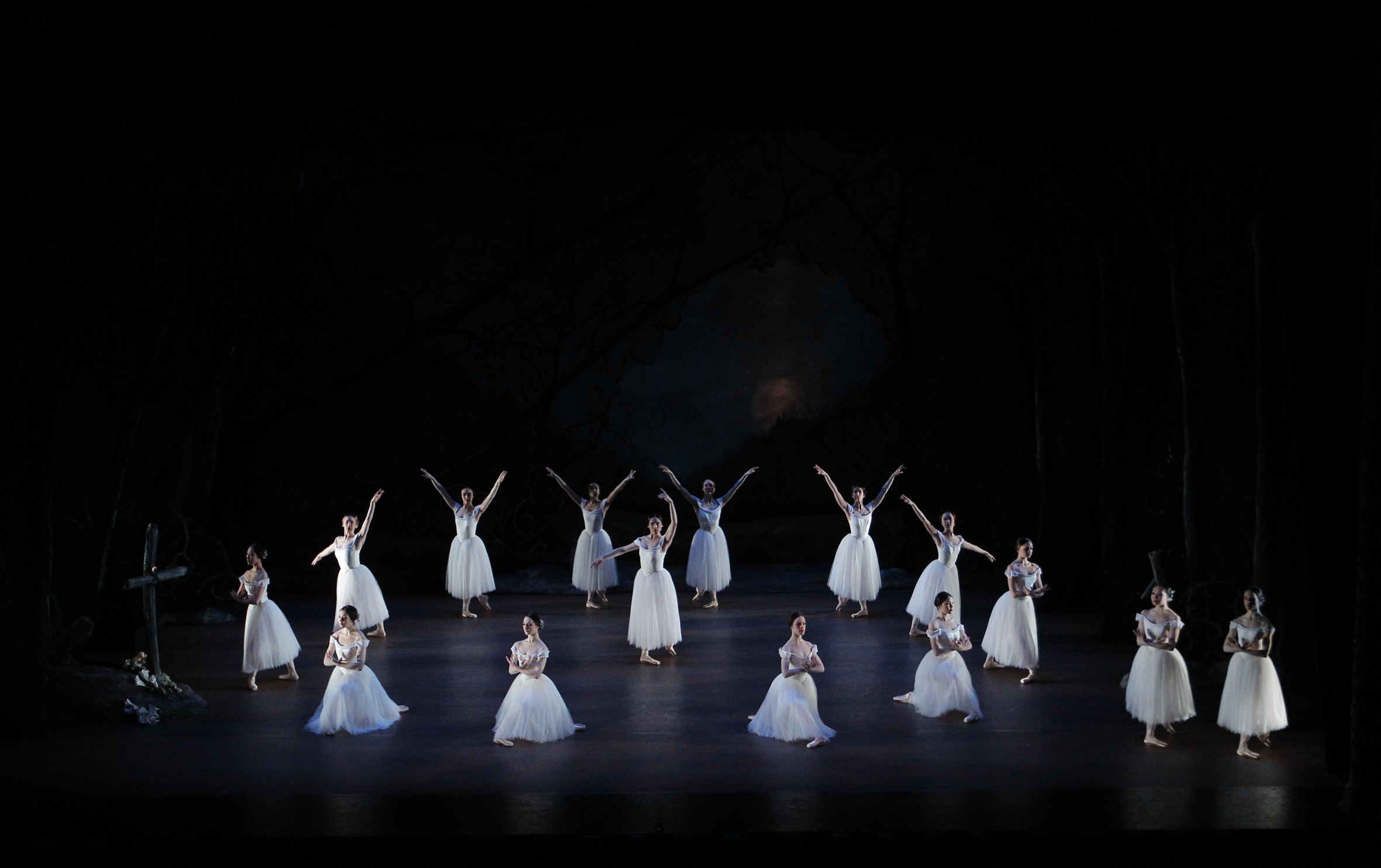 Birds eye view of dancers in white dresses on stage.
