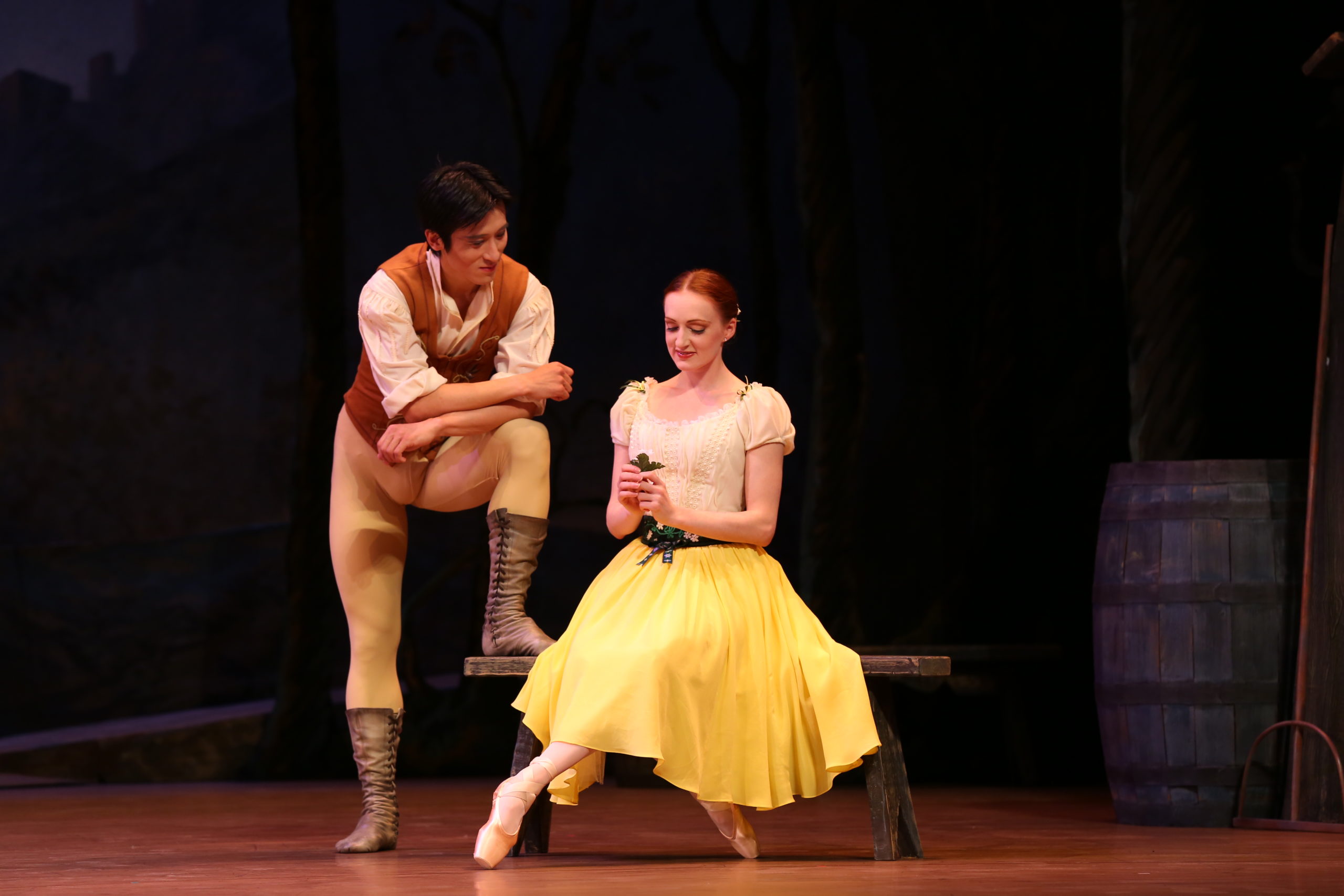 A scene from Giselle with two dancers, one sitting on a bench, the other offering a flower.