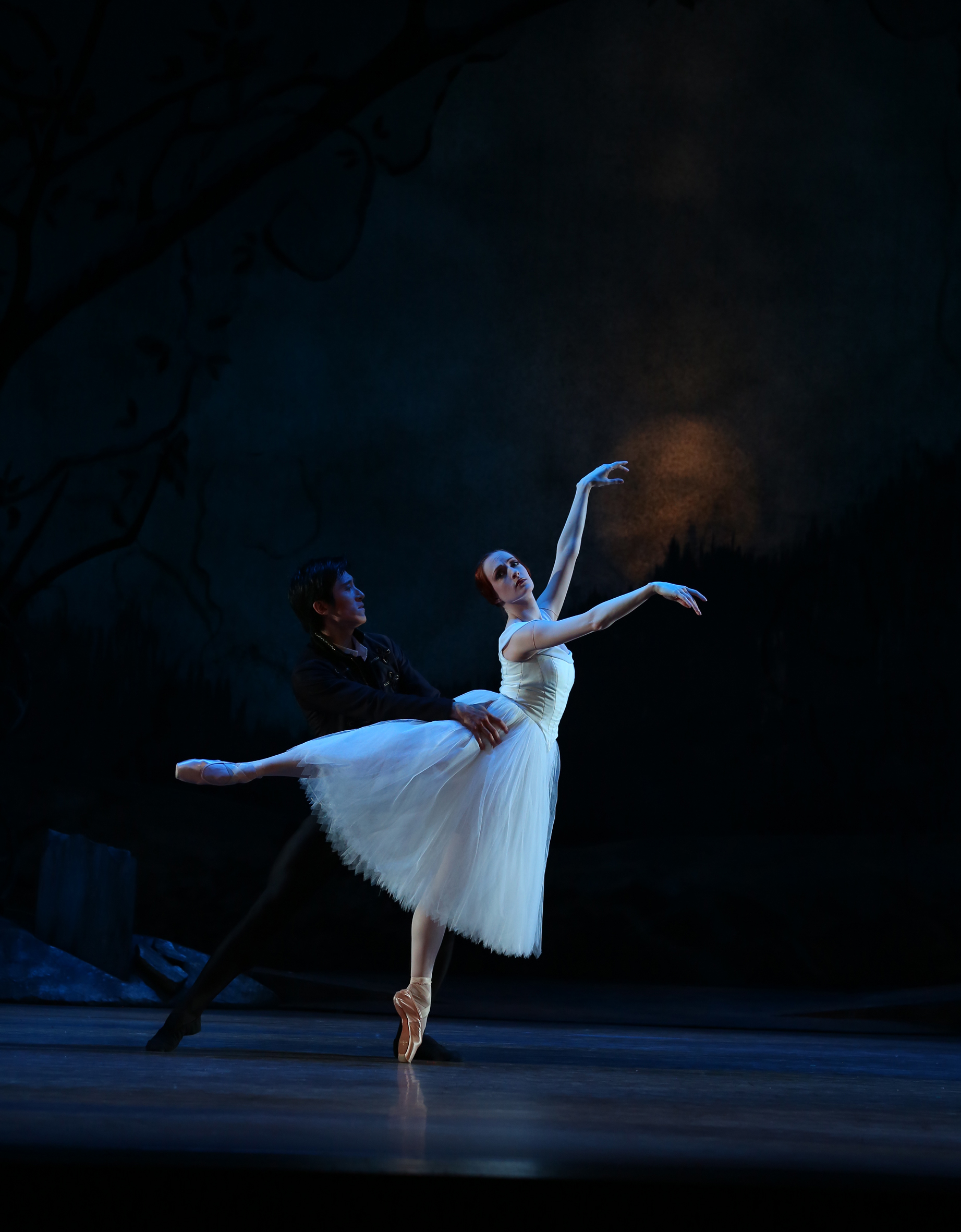 Two dancers from Giselle under dramatic lighting.